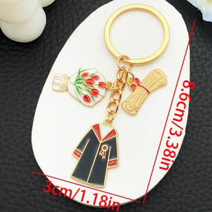 Detail of graduation keychain with diploma, robe and tulip charms on leather background