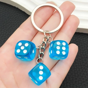 Portachiavi creativo con tre dadi blu trasparenti in resina tenuto da una mano