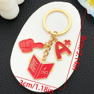 Macro shot of A+ academic keychain with graduation cap, thumb up, and red book charm