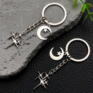 Silver star and crescent moon keychain set with polished metallic finish on rock background
