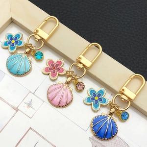 Détail de trois porte-clés fleurs et coquillages avec placage à l'or et cristaux bleus