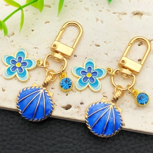 Porte-clés coquillage bleu profond et fleur avec cristaux bleus sur métal doré