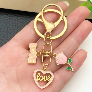 Porte-clés avec rose émaillée rose et cœur LOVE, tenu en main pour l'échelle