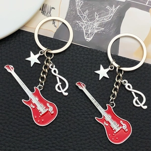 Detail of red electric guitar keychain with musical note and star charms on leather