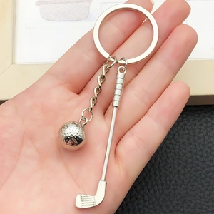 Détail d'un porte-clés club et balle de golf en argent tenu par une main pour l'échelle