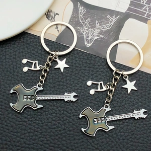Close-up of guitar keychain with musical note and star charm on black leather background
