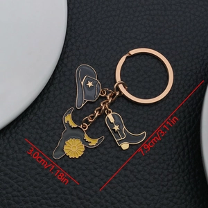 Detail view of gold enamel keychain with western cowboy hat, bull head and boot charms