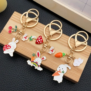 Three Chinese style rabbit keychains with carrot and strawberry enamel charms on wood