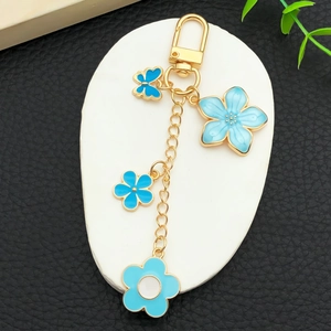 Porte-clés fleurs de cerisier bleues et papillon émaillés avec fermoir doré sur pierre
