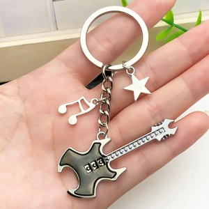 Guitar keychain with music note and star charms held by a hand in silver and grey tones