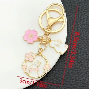 Detailed view of cherry blossom bunny keychain with dimensions on black leather background