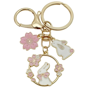 Golden keychain with cherry blossom pendants and white rabbit charms in a floral wreath