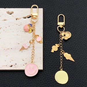 Porte-clés dorés avec glace en émail rose et smiley sur fond marbre et cuir noir