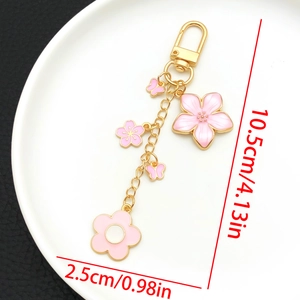 Detailed view of pink cherry blossom and butterfly enamel keychain with gold hardware