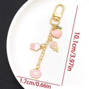 Detail view of pink enamel charms on golden U-shaped keychain with size measurements