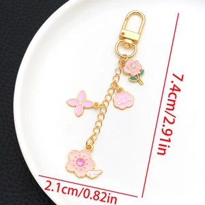 Détail des breloques émaillées rose et fleur de cerisier sur un porte-clés doré avec taille