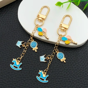 Golden keychain with blue rocking horse, crown, lollipop charms and colorful balloons