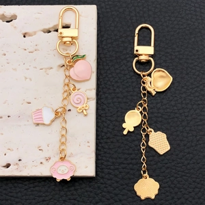 Golden keychain featuring pink enamel peach, cupcake, lollipop and lamb charms