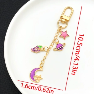 Détail d'un porte-clés doré de 10,5cm avec des breloques émaillées lune et étoile violettes