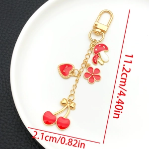 Détail du porte-clés doré en U avec breloques émaillées champignon coeur fleur cerise