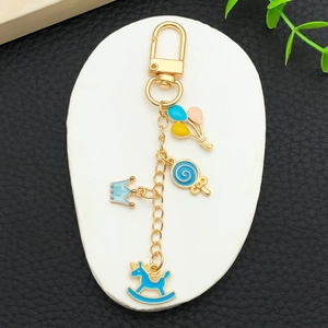 Golden keychain with blue crown rocking horse and candy charms on stone display