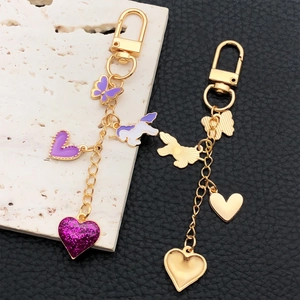 Porte-clés doré avec papillon en émail violet et breloques licorne sur socle texturé