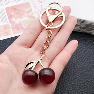 Cute resin red cherry keychain with gold metal clasp hanging as a bag charm ornament