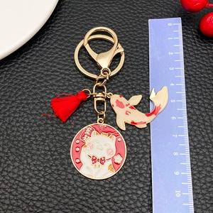 Fortune cat and koi metal keychain with red tassel on black leather background