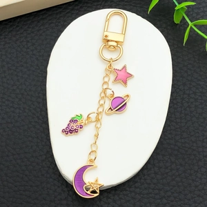 Porte-clés doré avec charms émaillés de cœur, étoile et lune violette sur socle