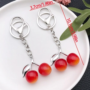 Cute red and yellow gradient resin cherry keychain with silver lobster clasp on a white plate