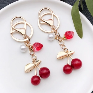 Portachiavi con ciliegie e fragole con perle e foglia d'oro su un piatto bianco