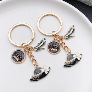 Porte-clés doré avec talons hauts en émail noir et breloques couronne sur assiette