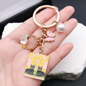 Porte-clés chat tarot en émail rose avec papillon doré, couronne et perle douce