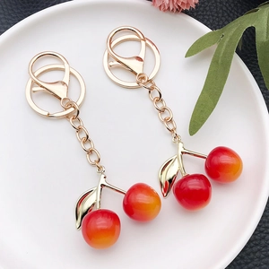 Porte-clés cerise en résine dégradé rouge et orange avec feuille dorée sur assiette