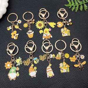 Emaille Bienen und Sonnenblumen Schlüsselanhänger Set auf schwarzem Leder Hintergrund