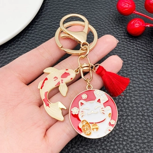 Japanese Maneki Neko and Koi keychain with red tassel on black leather backdrop