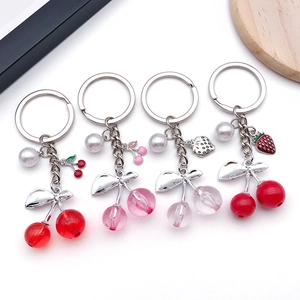 Detail of four colorful resin cherry keychains with pearls and silver leaves decorations