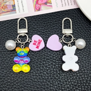 Colorful resin bear keychain with pearl and Be Mine heart charm on a black background