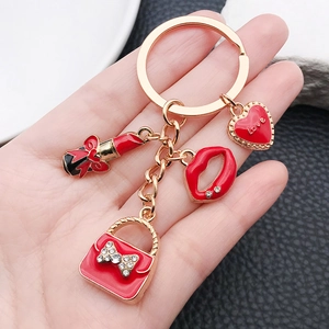 Portachiavi dorato con ciondoli smaltati rossi a forma di rossetto, cuore e borsa chic