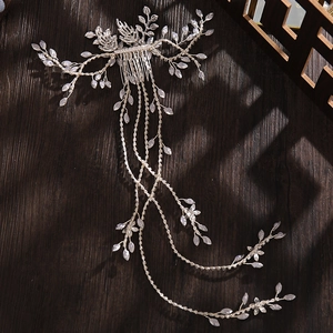 Dettaglio del pettine da sposa con cristalli e catene di nappe su superficie in legno