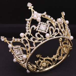 Detailed macro of golden baroque crown with intricate metalwork, pearls and square crystals