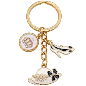Golden keychain featuring enamel charms of a high heel shoe, hat, and crown with pearls