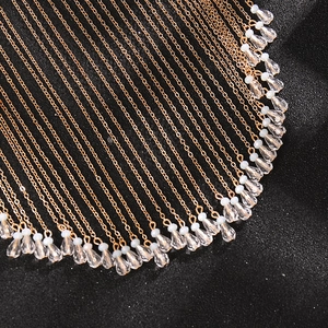 Detailed macro view of rose gold fringe chains with transparent teardrop crystal pendants