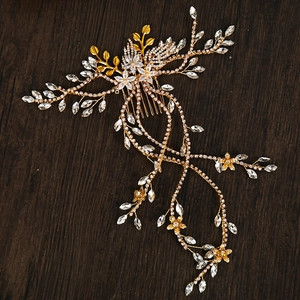 Dettaglio di pettine per capelli da sposa con foglie d'oro, strass e catene lunghe