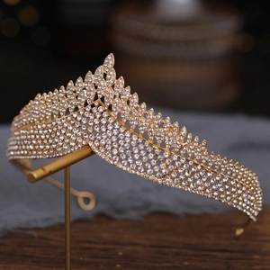 Detailed view of a gold bridal crown with shimmering rhinestones on a display stand