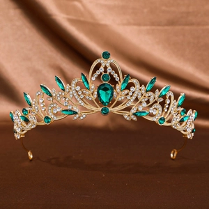 Detailed close-up of a vintage golden crown with emerald green gems and white crystals