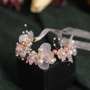 Macro shot of bridal wrist corsage with white petals, champagne pearls and silk ribbon