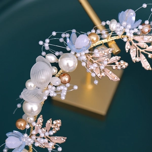 Detail of handcrafted bridal headband with pearls, golden leaves and blue flowers