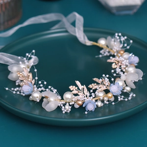Detail of floral bridal headband with pearls, rose gold leaves, and light blue petals