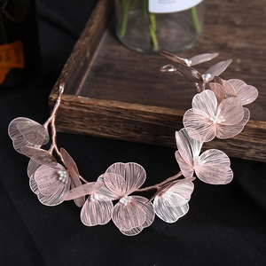 Detailed macro of rose gold wire-wrapped lace flowers with white pearls on bridal hairpiece